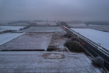 snow filled english countryside with car headlights on a dual carriageway road