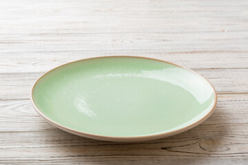 Perspective view of empty green plate on wooden background. Empty space for your design