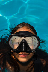 Close-up of the face of a girl swimming in a pool wearing a diving mask