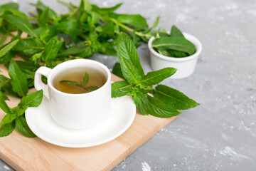 Cup of mint tea on table background. Green tea with fresh mint top view with copy space