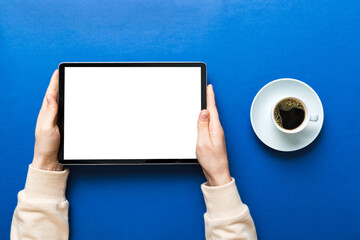 Close up image woman hands holding digital tablet with blank copy space screen for your text message or promotional content om table with cup of coffee. hands of a woman holding blank tablet device