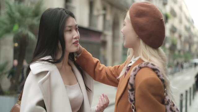 Asian woman caressing her lesbian partner's face in the street