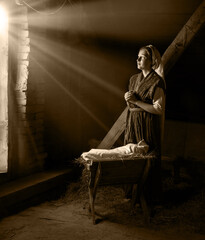 Mary sits in the stable near the manger with the baby