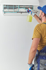 Repairman cleaning and fixing indoors AC unit.