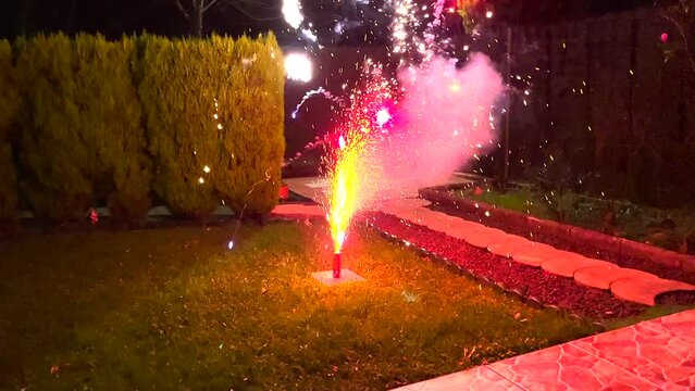 Ground-based Firecrackers starts to shoot out smoke and fire on the backyard during nighttime