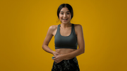 Ethnic female in studio yellow background Indian sport woman athlete girl lady measure waist size...