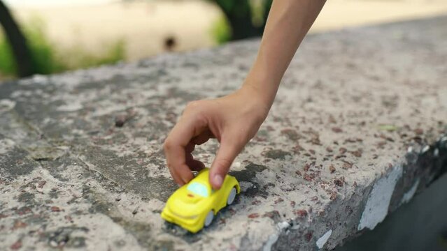 A child rides a toy car on a concrete fence