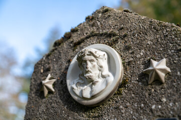 Jesusplakette zwischen zwei Sternen auf einem Grabstein auf einem Friedhof in Osnabrück