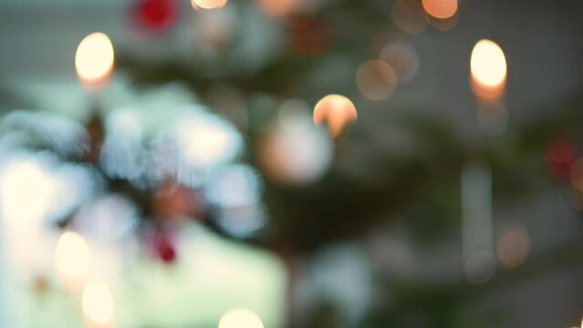 Weibliche Hand h&auml;ngt Kugel in Weihnachtsbaum. Effekt von unscharf zu scharf mit Bokeh