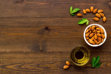 Fototapeta na wymiar Sweet almond oil in glass jar and almond seeds with green leaf