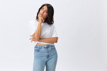 Woman in white t-shirt on white background brunette hands up gestures and signals poses in jeans emotion, lifestyle smiles, copy space