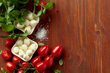 Mozzarella cheese with basil and tomatoes on an old wooden table.