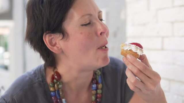 Brunette woman eats eclair cake. A hungry woman enjoys a delicious dessert