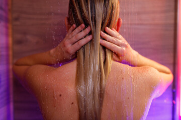 Beautiful woman washes her hair in the shower