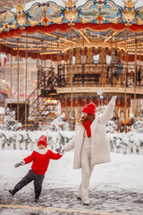 mother and son have fun at the Christmas market on the background of the carousel