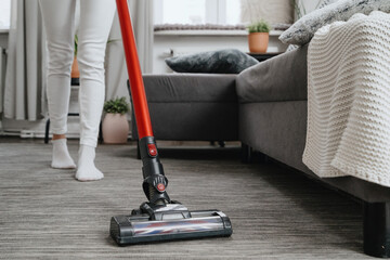 housewife cleanup with electric handheld vacuum duster in apartment