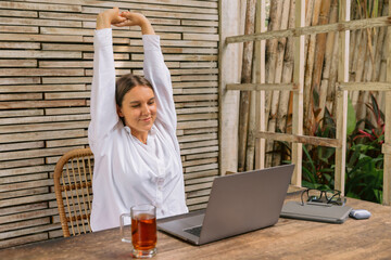 Young positive business woman sit indoors in co working using laptop computer.