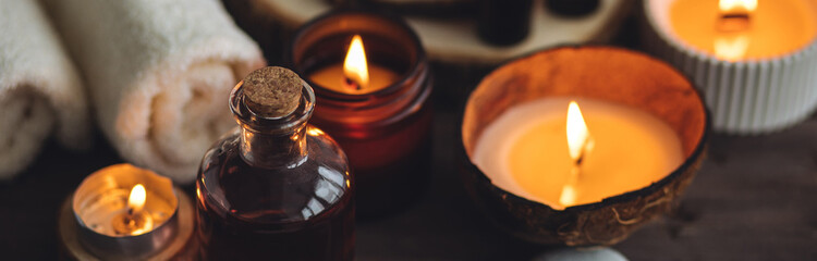 Concept of natural essential organic oils, Bali spa, beauty treatment, relax time. Atmosphere of relaxation, pleasure. Candles, towels, dark wooden background. Alternative oriental medicine. Banner