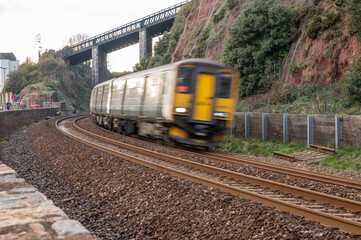 Obraz premium train on railway going fast on slight bend in Dawlish uk blurred motion with train