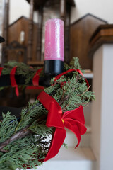 details of the Christmas bow of an advent wreath with colored candles