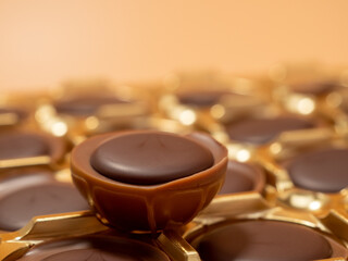 Chocolate candies on an orange background. Sweets with caramel. Round chocolates.