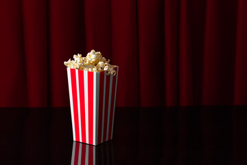 popcorn box on theater stage with red curtains and black background