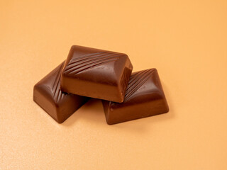 Chocolate candies on an orange background. Candies with filling.