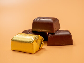 Chocolate candies on an orange background. Candies with filling.
