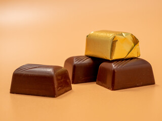 Chocolate candies on an orange background. Candies with filling.