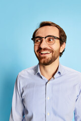 Obraz premium Half-length portrait of mature bearded man in eyewear expressing vivid emotions on his face isolated over blue background. Business, mental health, emotions concept
