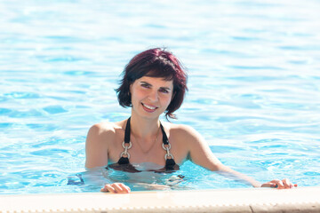 Swimming in pool brunette in black swimsuit, close-up.