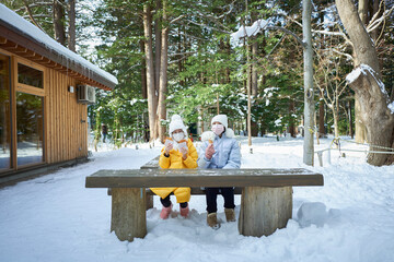 Beautiful Asian two sisters enjoy Hokkaido food while traveling in winter in Hokkaido - obrazy, fototapety, plakaty