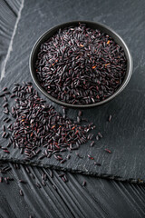 raw fresh black rice on black wooden rustic background