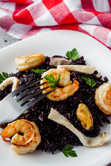delicious black rice with shrimps and seafood on a gray stone background