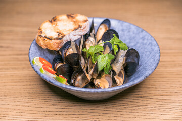 restaurant dish in shell mussels with sauce in a blue plate