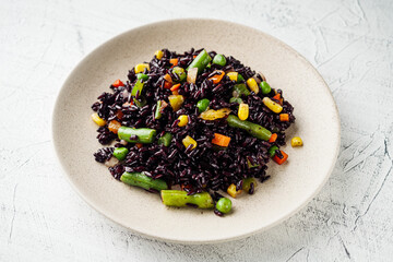 delicious black rice with vegetables on a white background