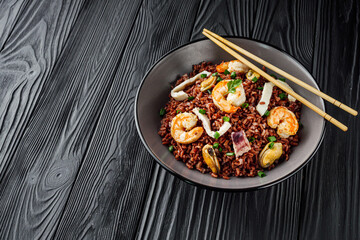 delicious red rice with shrimps and seafood on a black wooden rustic background