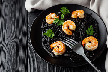 delicious black spaghetti pasta on a black rustic wooden background