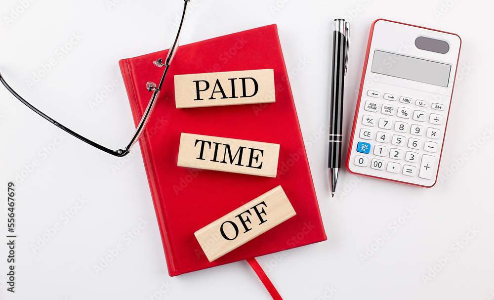 Poster paid time off text on wooden block on red notebook