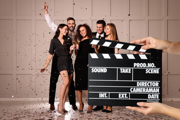 Shooting movie. Second assistant camera holding clapperboard in front of happy friends celebrating...