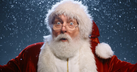 Photo of retired old man grey beard open mouth excited look see magical newyear creature make wish bring atmosphere wear santa costume coat spectacles headwear isolated blue color background