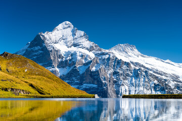 High mountains and reflection on the surface of the lake. Landscape in the highlands in the summertime. Dark sky. Photo in high resolution. Grindelwald, Switzerland. .