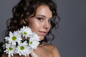 Beauuty portrait of a young woman with curly styled hair and white flowers.