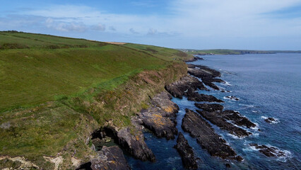 Vegetation-covered rocks on the shore of the Celtic Sea near the town of Clonakilty. Beautiful seascape. Nature on the Wild Atlantic Way. A natural attraction.