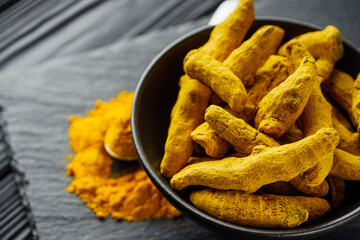 aromatic turmeric root on a black wooden rustic background