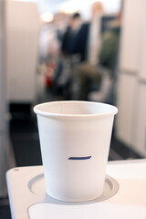 A drink in a paper cup on a passenger's table in a flying airplane