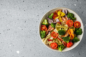 delicious colored farfalle pasta on a stone background