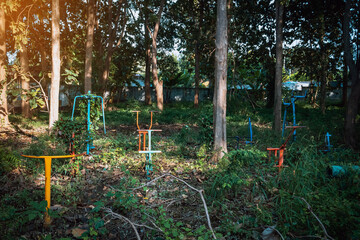 Old outdoor exercise equipment so worn out and covered in trees in outdoor exercise park. Old abandoned gym equipment on sports ground with overgrown grass. Unmaintained abandoned playground.