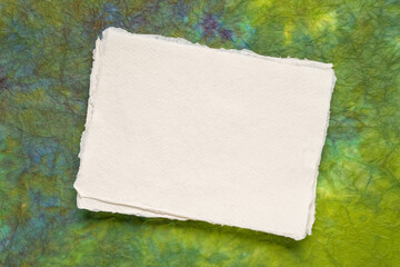 small sheet of blank white Khadi rag paper from South India against green marbled paper