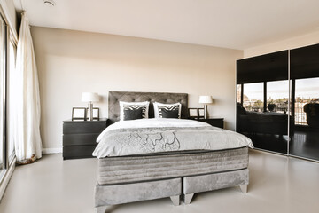 a bedroom with a bed, dressers and mirror in the corner wall to the other side of the room